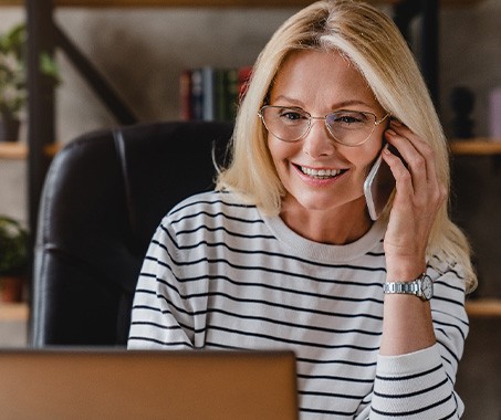 Woman with glasses smiling while talking on phone
