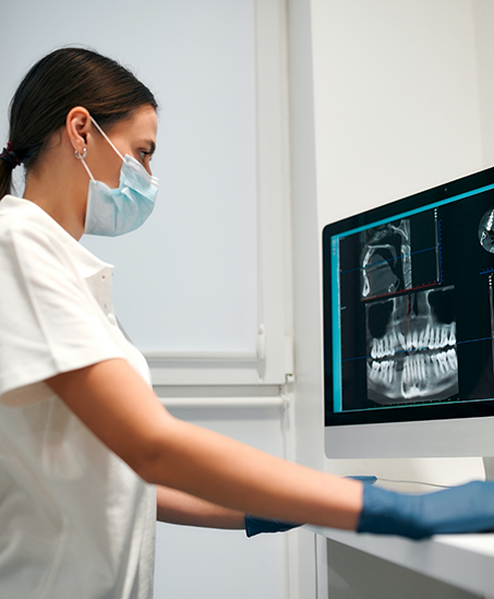 Dental team member looking at x rays of a patient's teeth