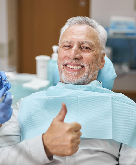 Smiling senior man giving a thumbs up in the dental chair