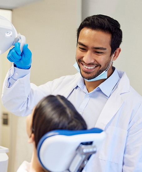 Dentist pulling light closer to examine patient’s mouth