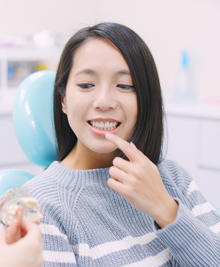 Woman pointing to her tooth while talking to her dentist