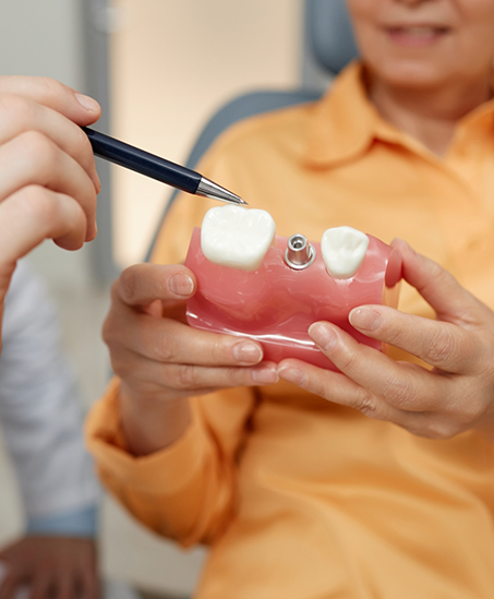 Dentist showing a model of a dental implant to a patient