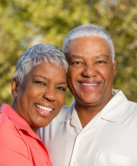 Senior couple smiling in front of trees