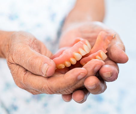 Hands holding a set of full dentures