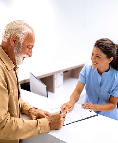 Senior man signing paperwork at the dental office