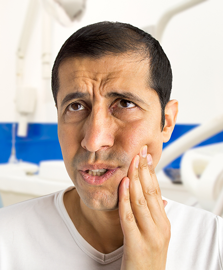 Man holding his cheek in pain while visiting his emergency dentist in Goodyear
