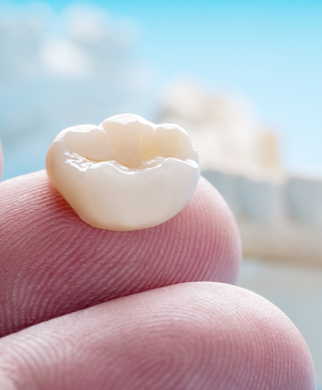Close up of a dental crown on a person's finger
