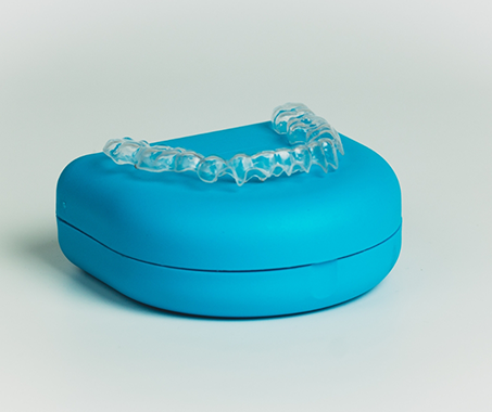 Invisalign aligner on top of its blue case