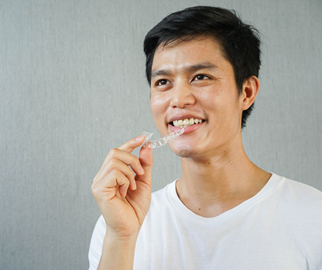 Smiling man holding an Invisalign tray
