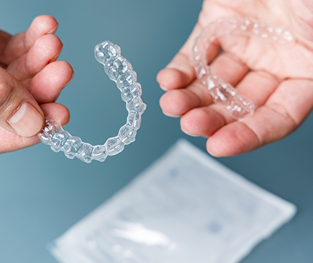 Two hands holding two clear aligners