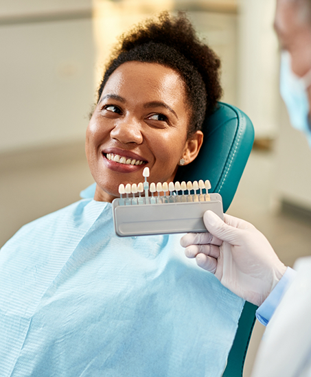 Goodyear cosmetic dentist holding a row of veneers in front of a patient's smile