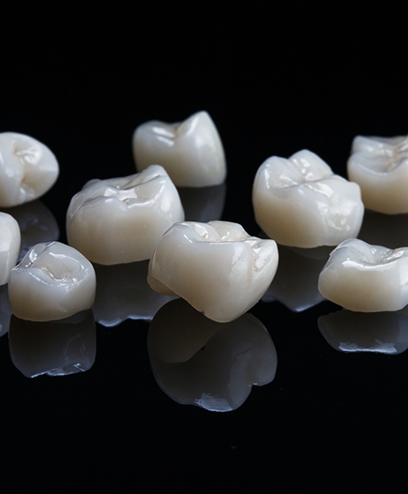 Several porcelain dental crowns against a black background