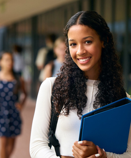 Teenage girl smiling while holding blue binder