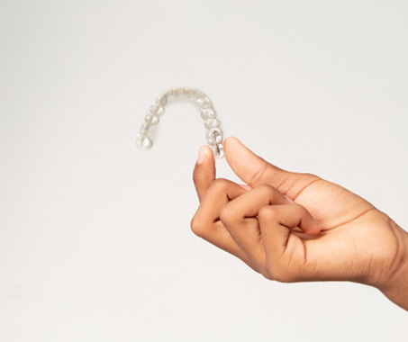 Closeup of teen holding clear aligner