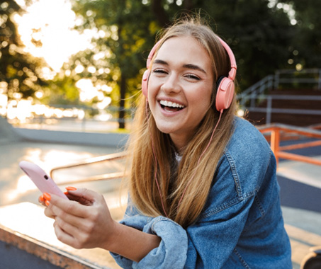 Teen girl smiling while listening to music outside