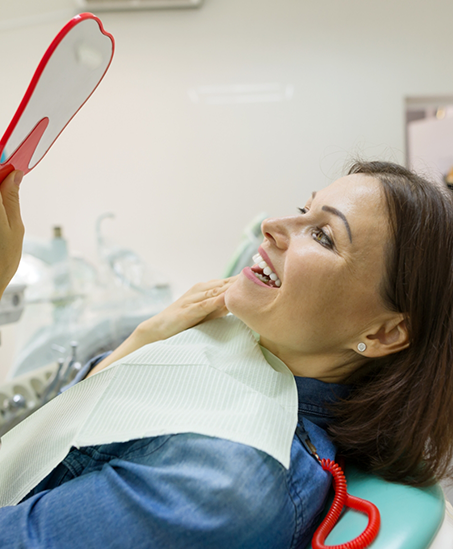 Dental patient looking in a mirror after a smile makeover in Goodyear