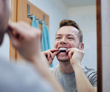 Man at home placing a whitening tray over his teeth