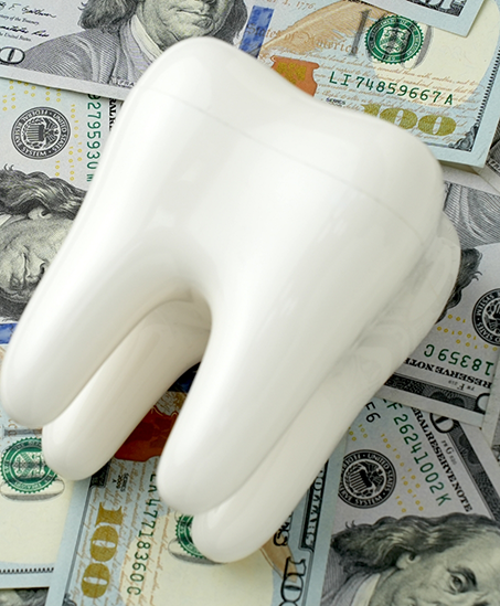 Model of a tooth laying on dollar bills