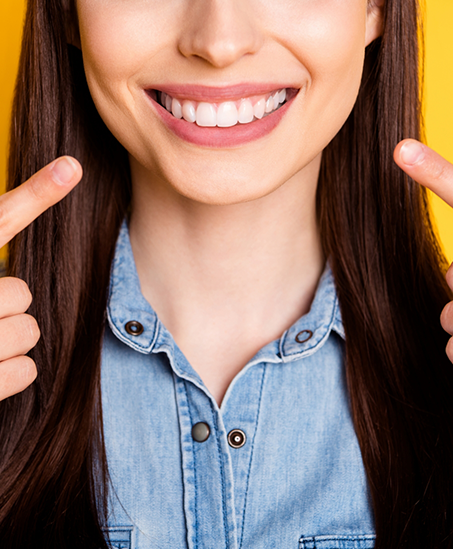 Close up of a smiling woman pointing to her teeth