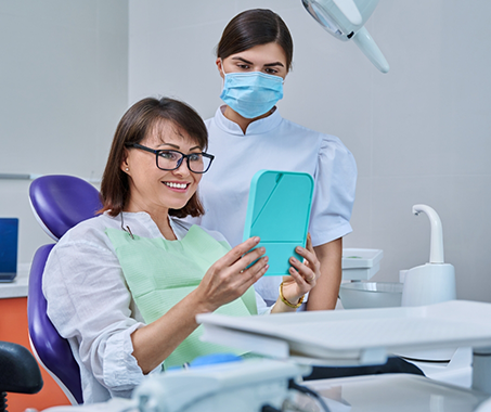 Dental patient admiring her new smile in a mirror