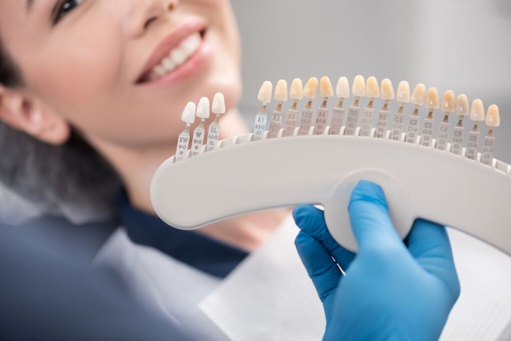 A dentist showing a woman a tooth shade guide.