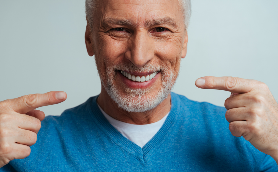 Man pointing to dentures, smiling