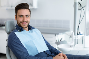 Man with facial hair sitting in dental chair and smiling